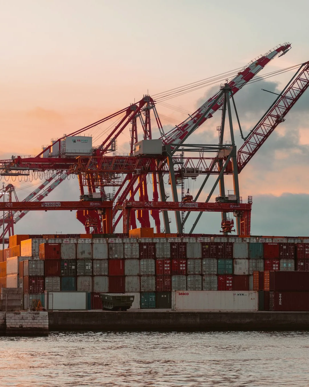 Contenedores de carga apilados en puerto al atardecer